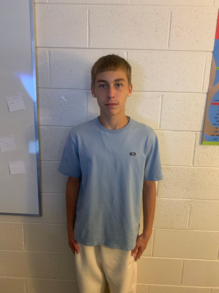 Vickers standing against a white wall with a blue shirt on.